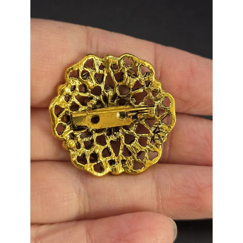 gold-tone brooch with a filigree design and amber/brown rhinestones